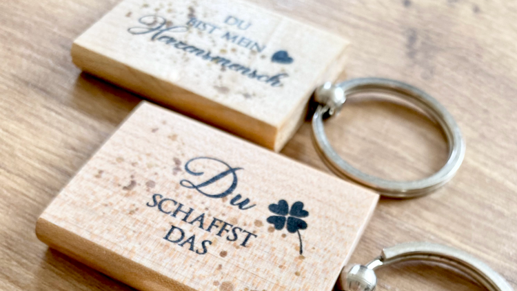 Handgefertigte Schlüsselanhänger aus Holz mit Schriftzügen.